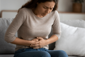 Frau hält ihre Hände auf den Bauch – Symbolbild für Verdauungsprobleme und Blähungen